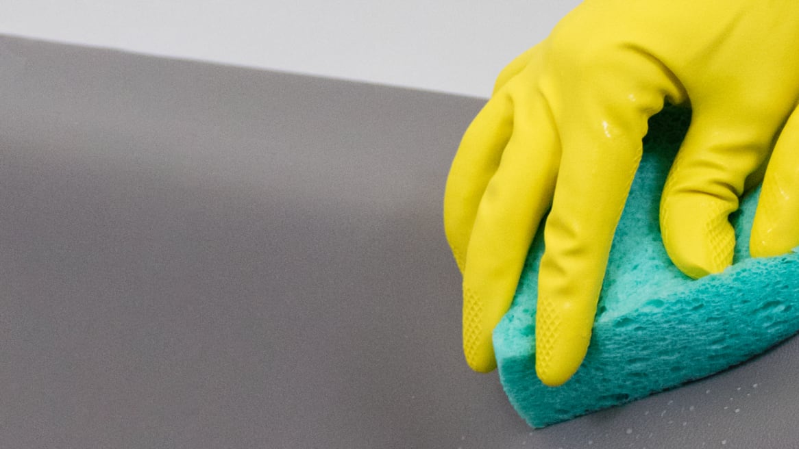 image showing gloved hand cleaning with a sponge
