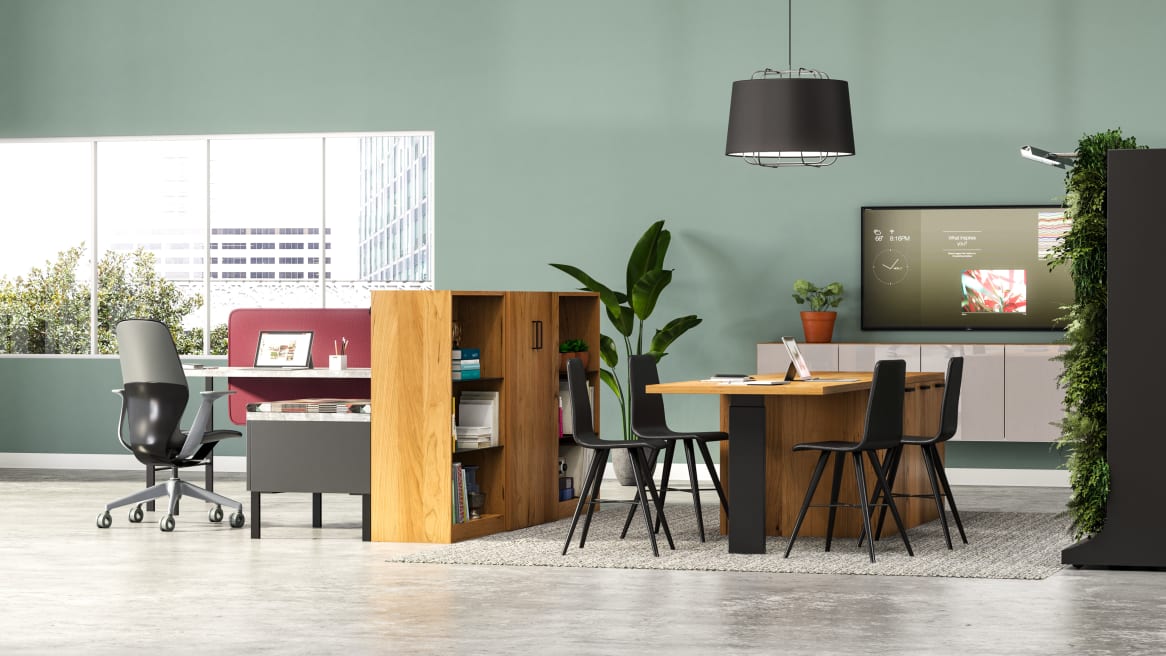 Nomadic Office space equipped with Elective Elements bookcases and storage, gray Bludot rug, black Bolia beaver chair with a TV screen on the back.