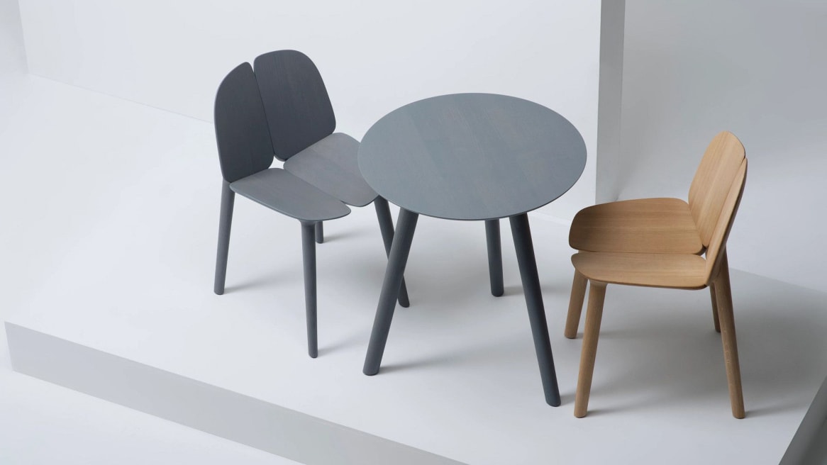 A gray and a natural ash Osso Chairs by Mattiazzi in front of a round gray Osso Table.