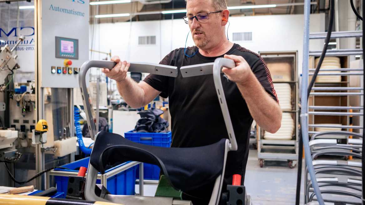 Steelcase worker assembling a chair in an industrial environment