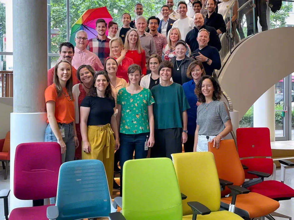 Steelcase employees pose behind Pride chair display in Munich, Germany.