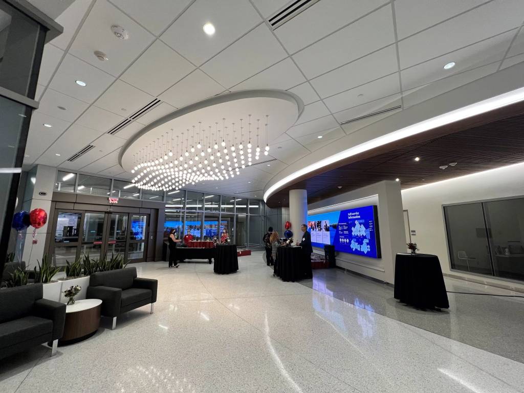 Picture of a clinic entry room with various seating, dynamic lighting, and a large monitor wall