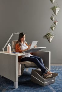 Woman seated on a Brody chair with lamp while using an iPad