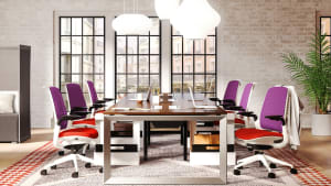 Six Steelcase Series 1 office chairs with red orange seats and purple backs a in meeting room