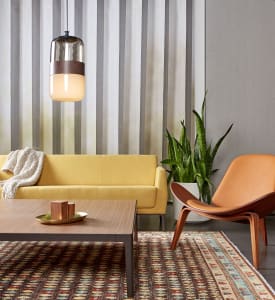A yellow Visalia three-seat sofa is seen in front of a gray wall and next to a Carl Hansen CH07 Shell Chair with a wood CG_1 square table in front of it