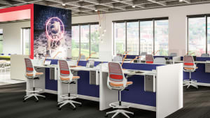 Workstations in an office space are created using Steelcase Series 1 task chairs with orange upholstery contrasting against blue Answer panel systems from Steelcase
