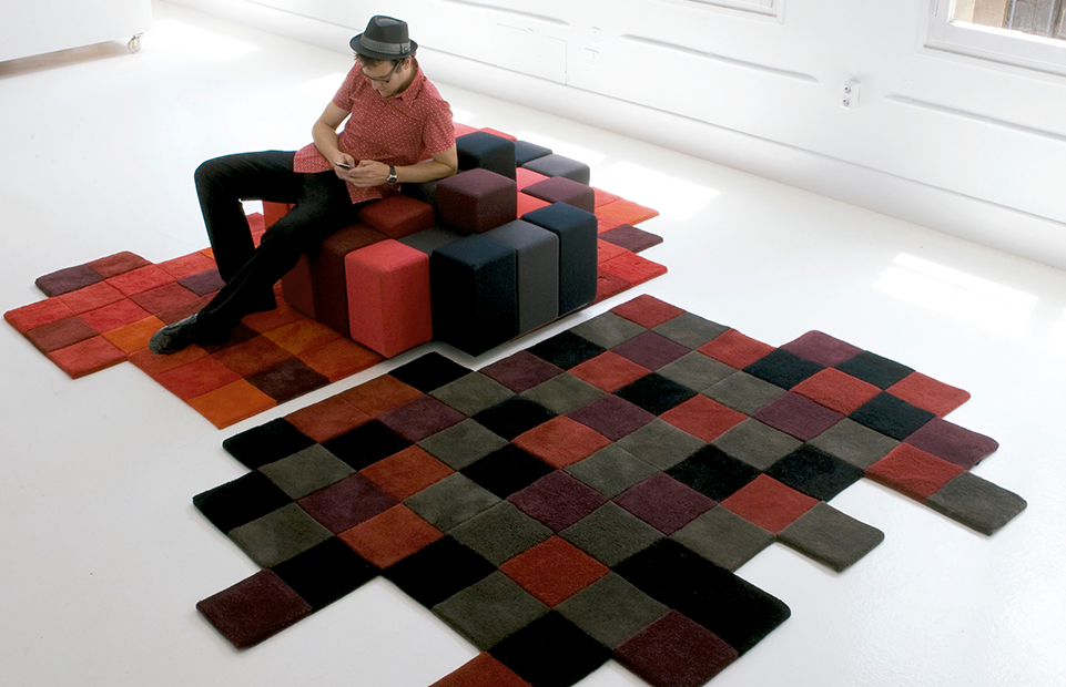 man seated on a puff and underneath there is a dolorez red rug