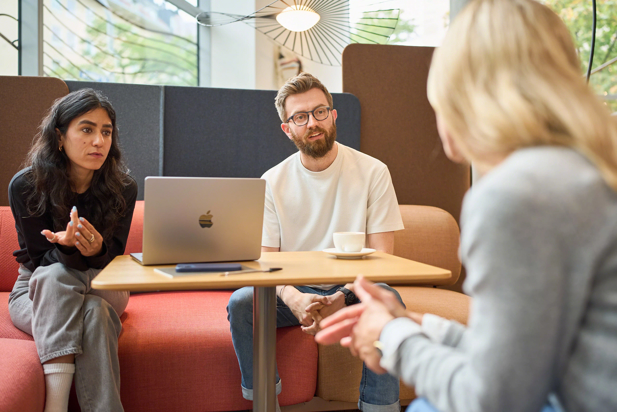 3 people discussing while seated on the Coalesse Ensemble Lounge System at the Munich LINC.